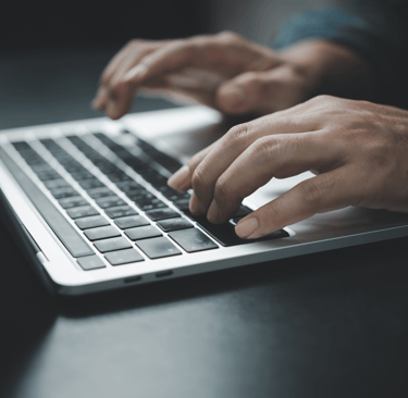 Close-up of hands typing on a laptop keyboard, representing research and decision-making in selecting the best IT solutions f
