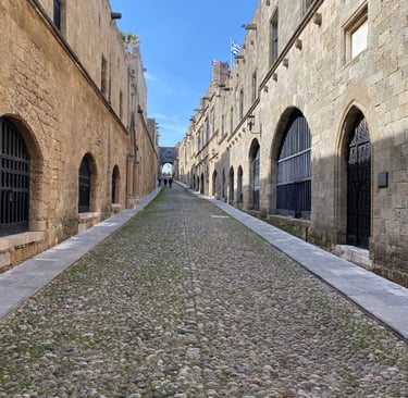 Historic cobblestone street of the Knights in Rhodes Old Town with medieval stone architecture and arched windows.