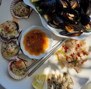 Fresh seafood platter with steamed mussels, baked scallops in shells, and white fish ceviche served with lemon.