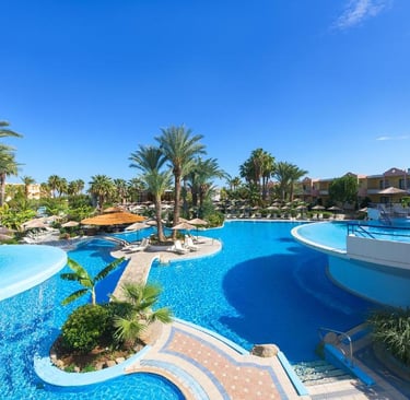 Luxury tropical resort swimming pool with palm trees, blue water, and sun loungers at Atrium Palace 