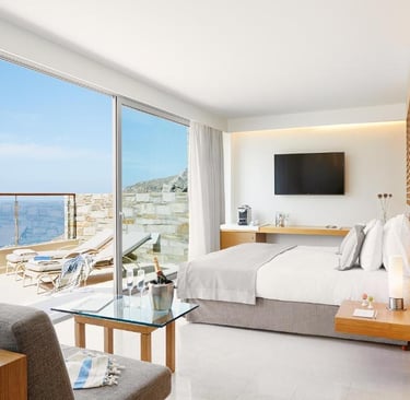 Luxury hotel room with a sea view balcony, white bedding, and modern minimalist decor.