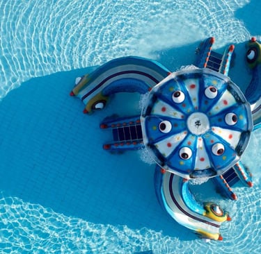 Aerial view of a colorful octopus-themed water slide in a clear blue resort swimming pool.