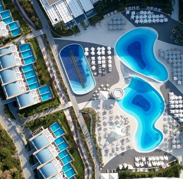 Aerial view of a luxury Princess Andriana hotel with curved swimming pools and private villa patios.