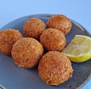 Crispy golden-brown falafel balls served on a blue plate with a fresh lemon wedge.