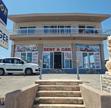 Marathon Rent a Car office building in Rhodes with a white rental car parked in front.