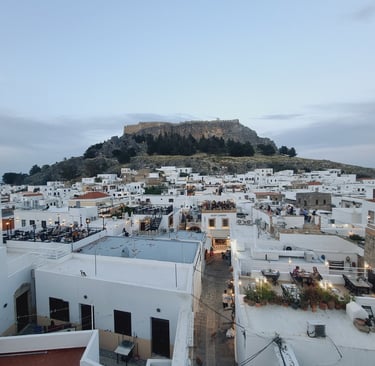 Panoramic view of white houses in Lindos village with the ancient Acropolis on a hill in Rhodes, Greece.