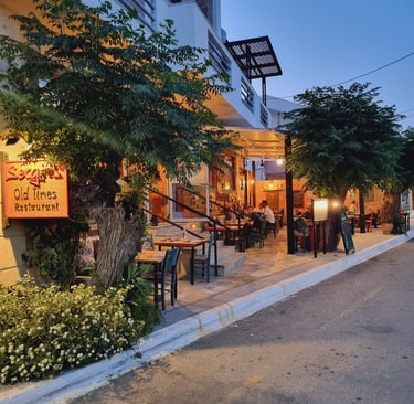 Diners enjoying an evening meal at the Old Times Restaurant outdoor patio under trees.