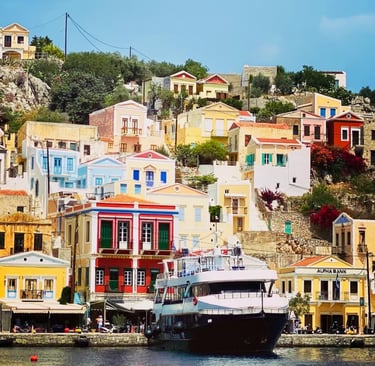 Colorful neoclassical houses on a hillside overlooking a cruise boat in Symi Island harbor, Greece.