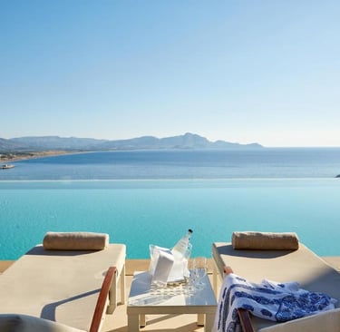 Luxury infinity pool overlooking the Mediterranean Sea with sun loungers at a tropical resort.