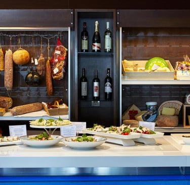 Gourmet Italian deli display featuring cured meats, artisan cheeses, wine bottles, and fresh appetizers.