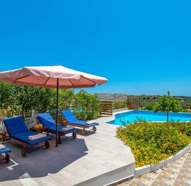 Luxury villa terrace with blue lounge chairs, pink umbrella, and a private swimming pool.