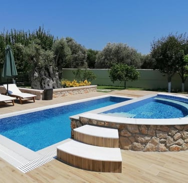 Luxury backyard swimming pool with a stone-clad hot tub, sun loungers, and lush garden landscaping.