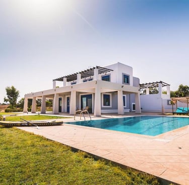 Luxury white vacation villa with a private outdoor swimming pool and sunny garden terrace.