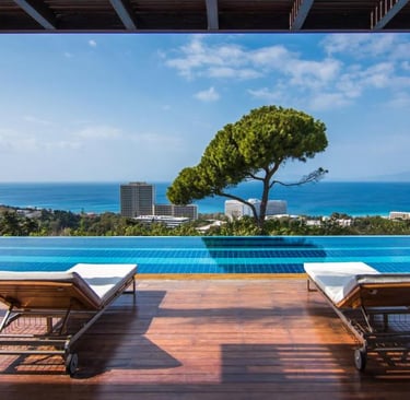 Luxury infinity pool with sun loungers overlooking the ocean at a Mediterranean resort.