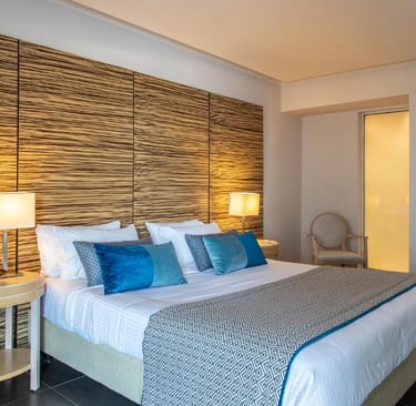 Modern luxury hotel room with blue pillows, textured wood headboard, and bedside lamps.