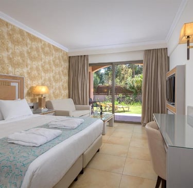 Luxury hotel room with a double bed, patterned wallpaper, and glass doors leading to a private garden patio.