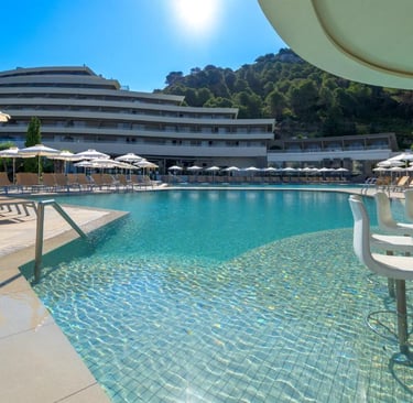 Luxury resort swimming pool with a swim-up bar, white umbrellas, and modern hotel architecture.