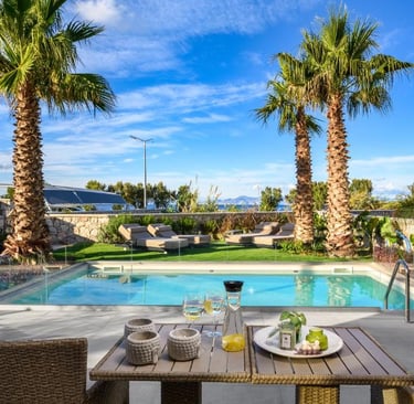 Luxury villa patio with pool view, palm trees, and outdoor dining table under a blue sky.