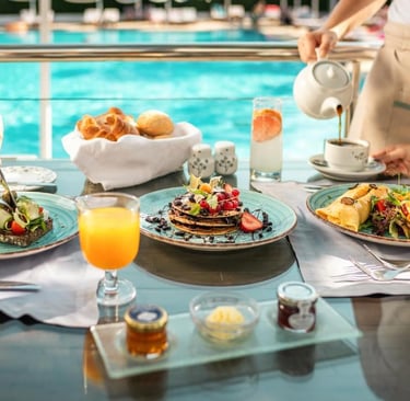Gourmet breakfast with pancakes, toast, and orange juice served poolside at a luxury resort.