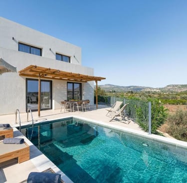 Luxury modern villa with a private infinity pool and sun loungers overlooking a scenic Greek valley.