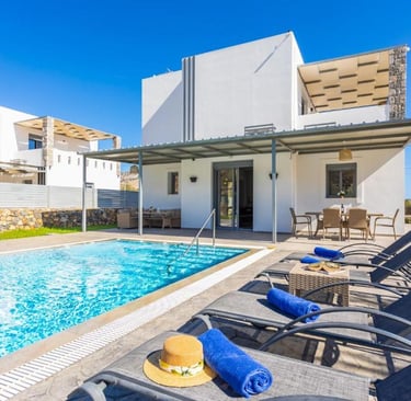 Luxury modern villa with private swimming pool, sun loungers, and outdoor dining patio under a clear blue sky.