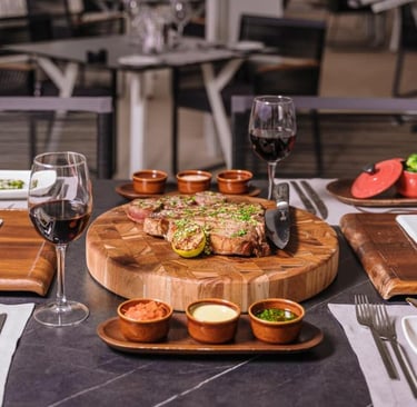 Gourmet steak dinner with red wine and side dishes on a restaurant table.
