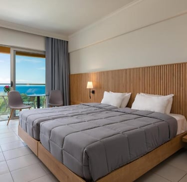 Modern hotel room with twin beds, wood paneling, and a private balcony overlooking the blue ocean.
