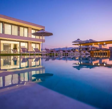 Luxury modern villa with a large infinity swimming pool and lounge chairs at sunset.