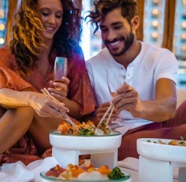 A happy couple enjoying a romantic sushi dinner with wine at a luxury outdoor restaurant.