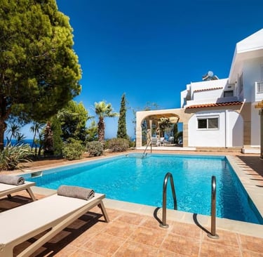 Luxury white villa with private swimming pool and ocean view terrace in a tropical garden.