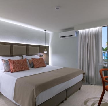 Modern hotel bedroom with a king-size bed, sea view balcony, and elegant interior design.