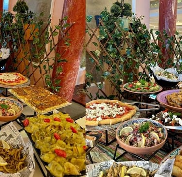 A gourmet hotel buffet spread featuring Mediterranean dishes like pizza, dolmas, salads, and fried seafood.