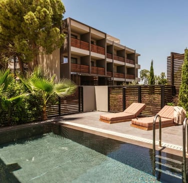 Luxury resort pool with two lounge chairs on a private terrace surrounded by tropical palm trees.
