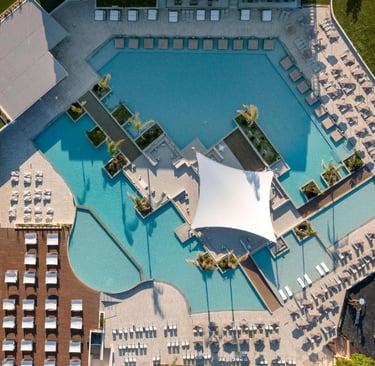 Aerial view of a luxury resort swimming pool with lounge chairs and a modern canopy.