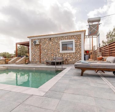 Luxury stone villa with a private swimming pool and cushioned sun loungers on a modern patio.
