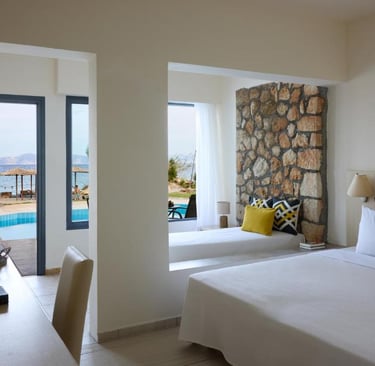 Modern hotel suite with stone wall, sea view balcony, and pool access.
