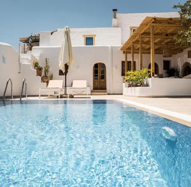 Luxury Greek villa with a private turquoise swimming pool, white architecture, and sun loungers.