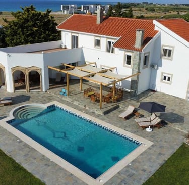 Luxury white villa with red tile roof and private swimming pool overlooking the Mediterranean sea.