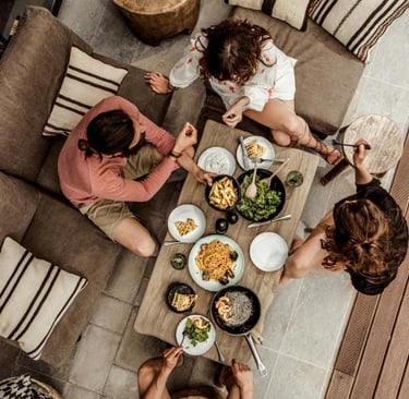 Aerial view of friends sharing a Mediterranean dinner on a modern outdoor patio lounge.