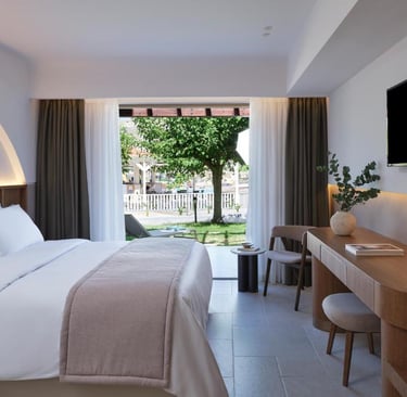 Modern luxury hotel room with a minimalist wooden desk and view of a garden terrace.