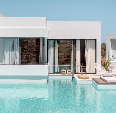 Modern luxury villa with a private turquoise swimming pool and sun loungers under a clear sky.