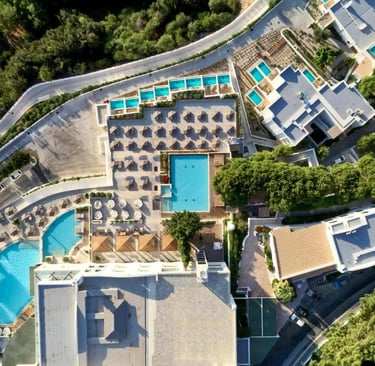 Aerial view of a luxury resort with multiple swimming pools, sun loungers, and umbrellas.