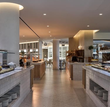 Luxury hotel buffet area featuring a variety of desserts on marble counters in a modern restaurant.