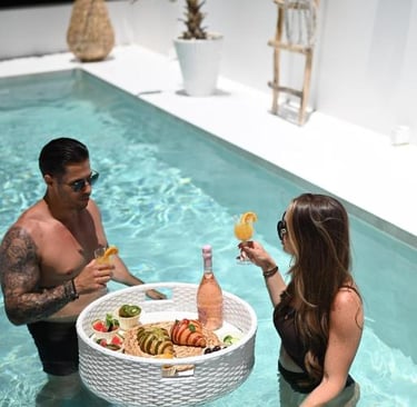A couple enjoys a luxury floating breakfast tray with cocktails in a private pool.