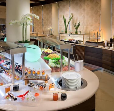 Luxury hotel buffet featuring a fresh sushi display, salad bar, and gourmet appetizers in a modern dining room.