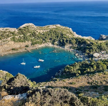 Aerial view of Anthony Quinn Bay in Rhodes, Greece, with yachts anchored in turquoise Mediterranean waters.