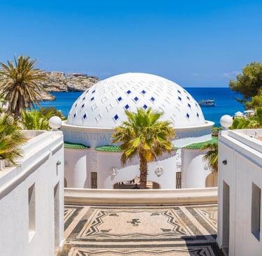 White domed building with blue tiles at Kallithea Springs in Rhodes, Greece overlooking the sea.