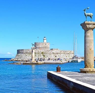 Mandraki Harbor in Rhodes Greece featuring deer statues and the Fort of Saint Nicholas.