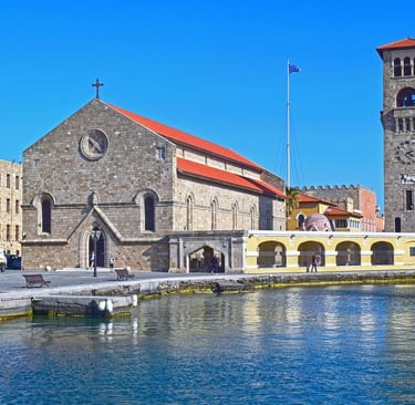 The historic Church of the Annunciation and stone clock tower on the Rhodes waterfront.