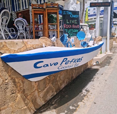Cavo Pefkos Cocktail Bar entrance in Rhodes, Greece featuring a blue and white decorative boat sign.